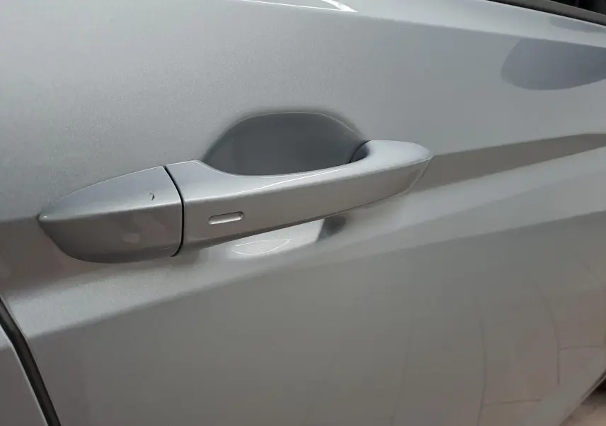 Poignée de porte côté gauche en gros plan sur Volkswagen Touran 2025 couleur Argent Dolomite métallisée.