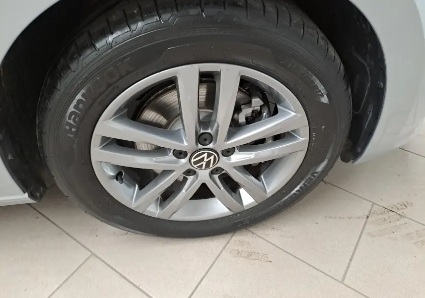 Gros plan sur la roue avant droite argentée avec jante alliage et logo Volkswagen sur un Touran 2025 Argent Dolomite.