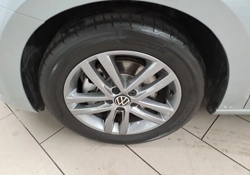 Gros plan sur la roue avant gauche argentée avec jante alliage et logo Volkswagen du Touran 2025 Argent Dolomite.