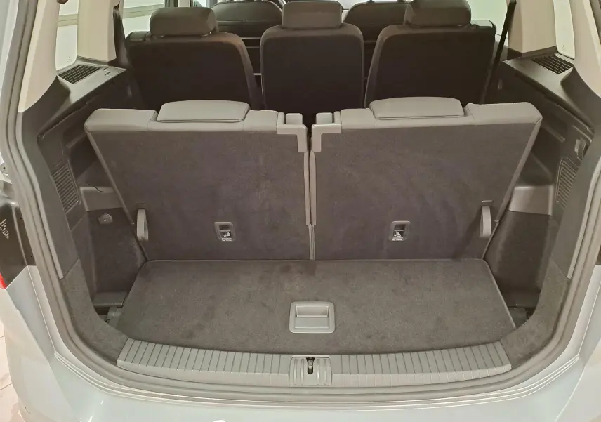Vue arrière du coffre du Volkswagen Touran 2025 argent Dolomite avec sièges rabattus et espace de chargement visible.