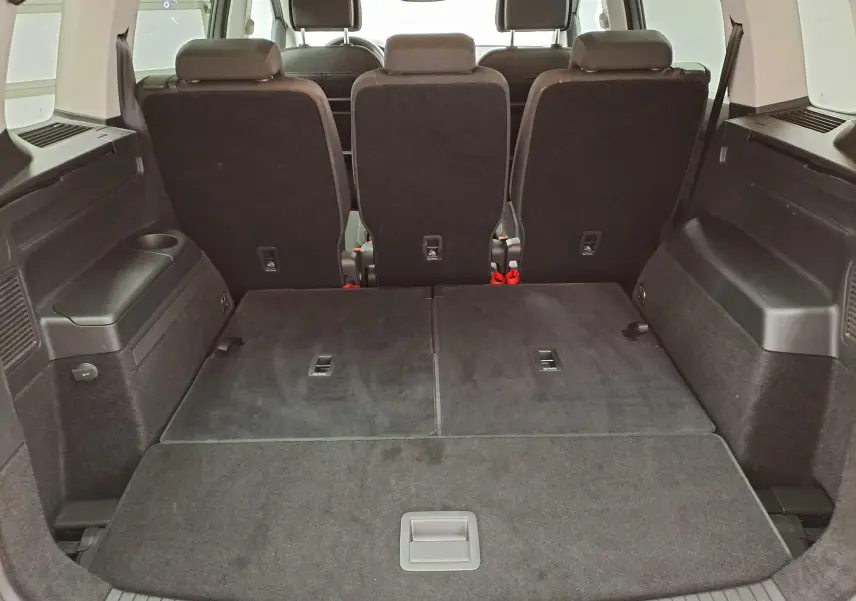 Vue depuis le coffre du Volkswagen Touran 2025, sièges arrière noirs partiellement rabattus, espace de chargement spacieux.
