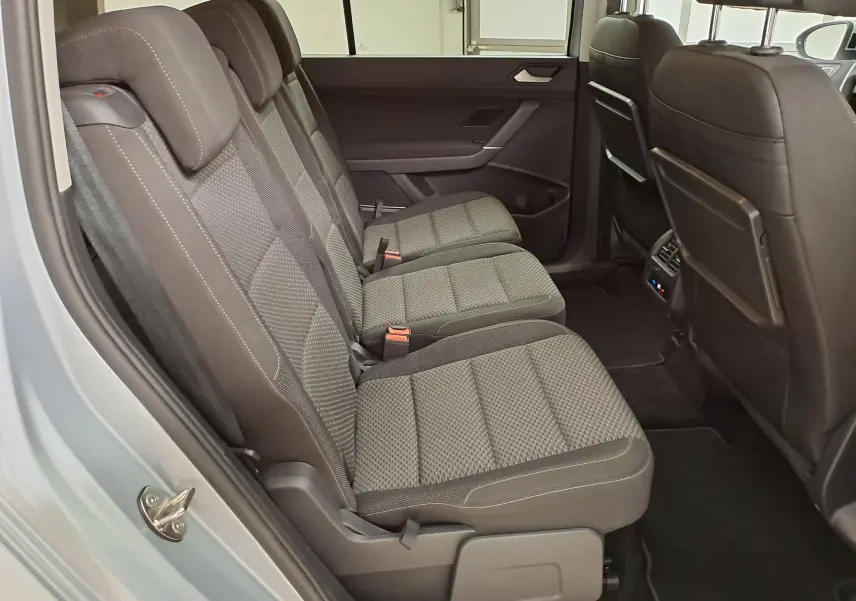 Vue latérale des sièges arrière en tissu gris du Volkswagen Touran 2025, avec porte ouverte côté gauche.