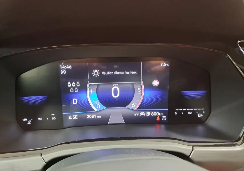 Tableau de bord numérique du Volkswagen Touran 2025 affichant vitesse à 0 km/h et message d'alerte feux éteints.