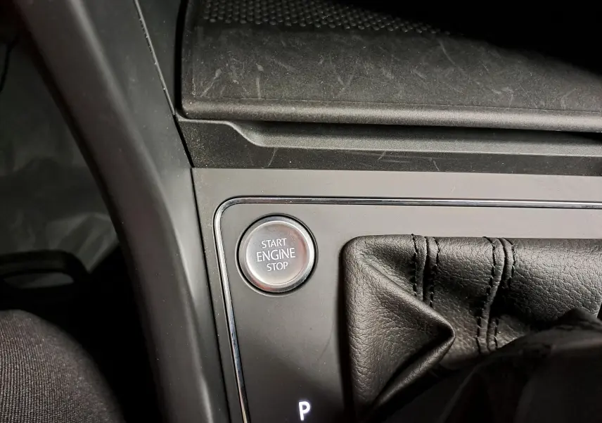 Détail intérieur montrant le bouton start/stop moteur et le soufflet de levier de vitesse en cuir noir.