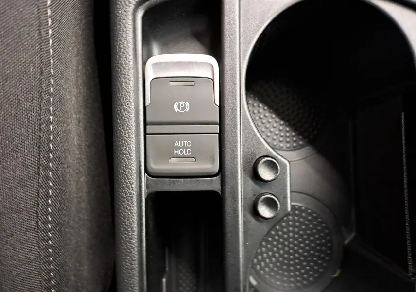 Gros plan sur la console centrale avec frein à main électronique et porte-gobelets du Volkswagen Touran 2025 argent Dolomite.