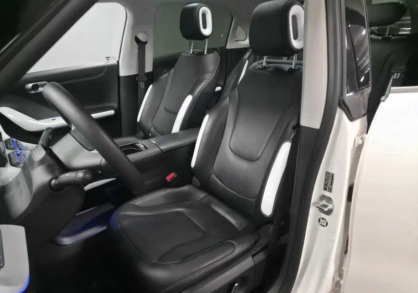 Vue intérieure côté conducteur d'une Smart Electric blanche 2024 avec sièges cuir noirs et inserts blancs.