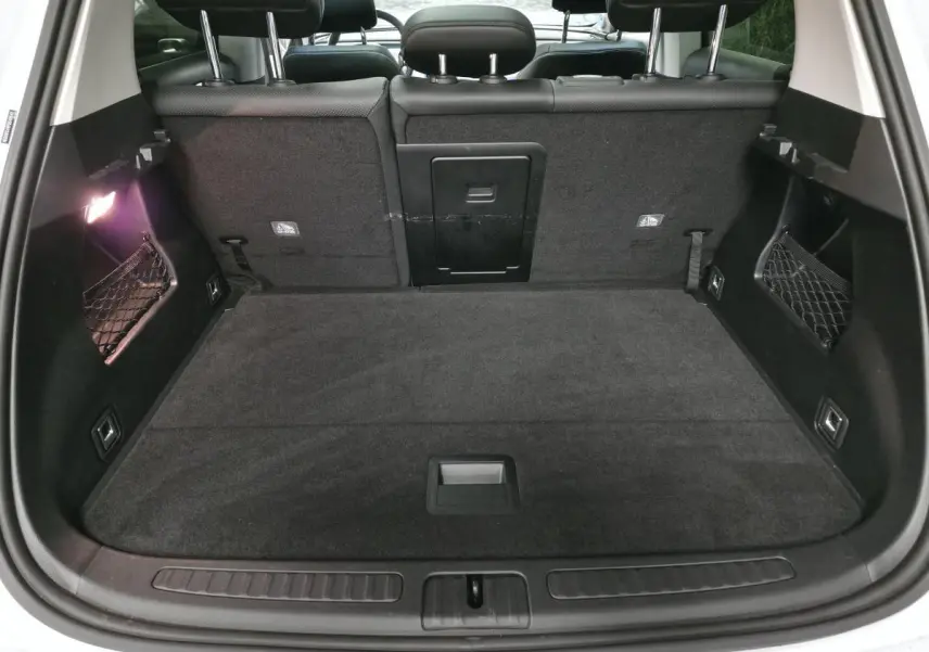 Vue arrière du coffre noir spacieux du Smart #1 Electric Premium blanc 2024 avec banquette arrière et filets latéraux.