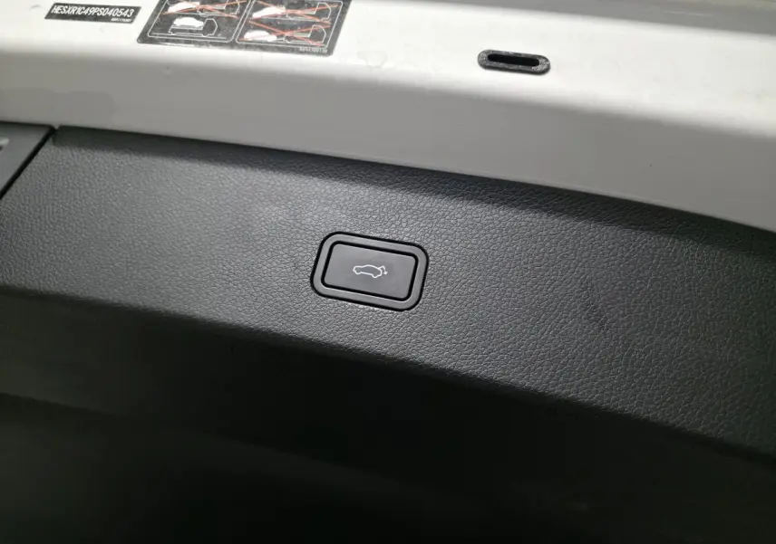 Gros plan sur le bouton d'ouverture électrique du coffre, intérieur noir et blanc du Smart #1 Electric 2024.