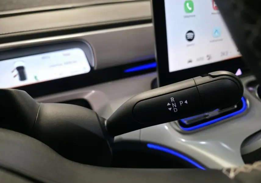 Gros plan sur la commande de boîte automatique noire dans l’habitacle lumineux du Smart Electric blanc 2024.