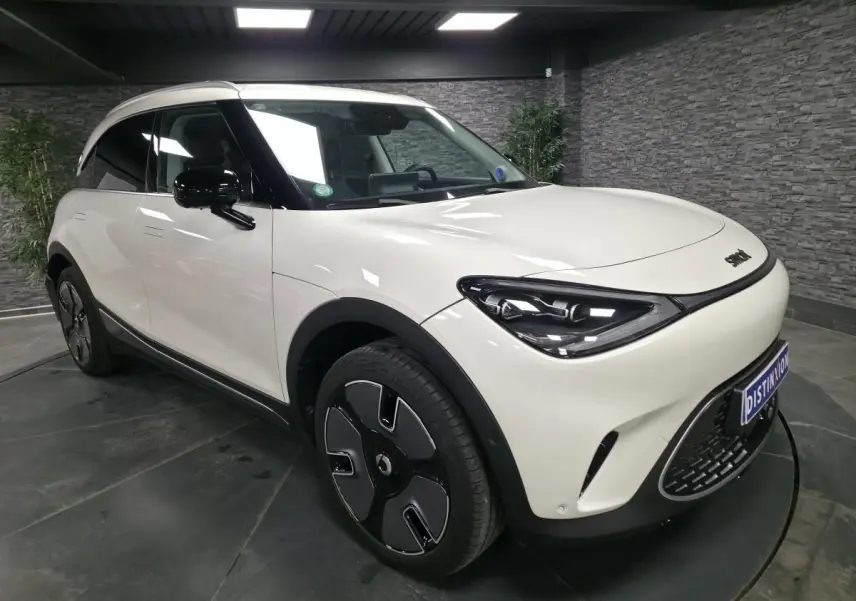 Vue 3/4 avant droit d'une Smart #1 électrique blanche avec jantes noires et toit panoramique en verre.