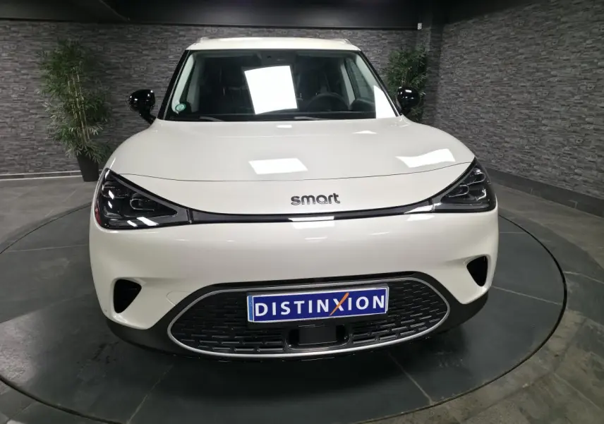 Vue avant d'une Smart #1 électrique blanche avec phares LED noirs et calandre basse distinctive.