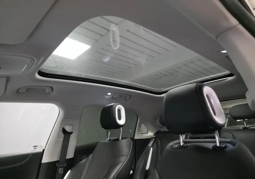 Intérieur de la Smart #1 électrique 2024, vue arrière montrant les sièges noirs avec appuie-têtes lumineux et toit panoramique en verre.