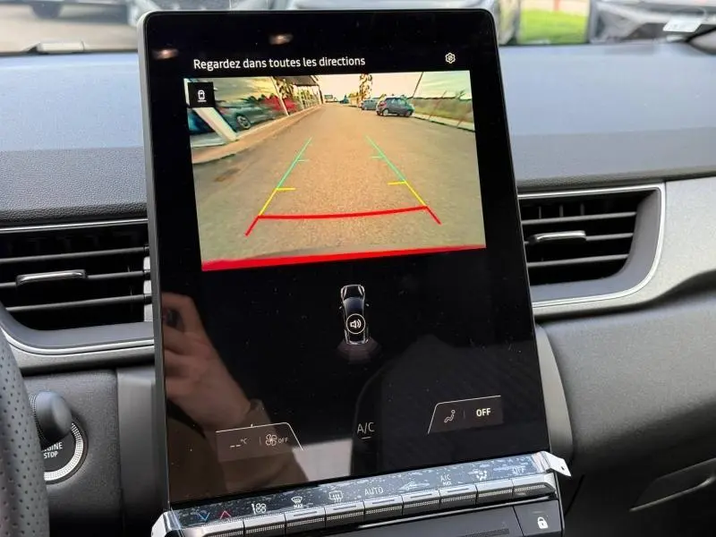 Écran central du Renault Captur 2025 affichant la caméra de recul avec vue arrière sur route et marquages de guidage colorés.