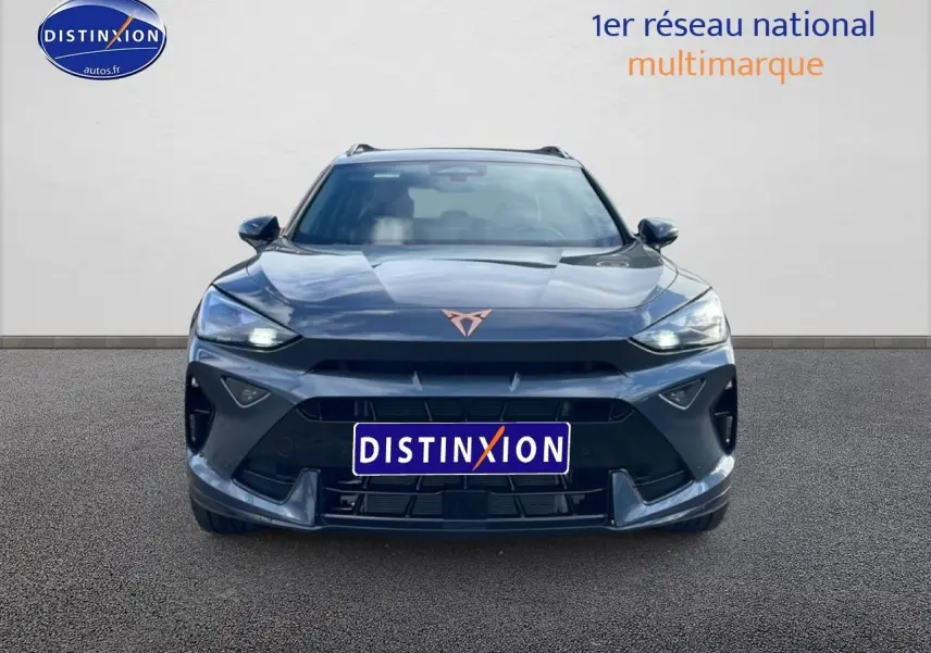 Vue frontale d'un CUPRA Formentor gris magnétique 2026 avec phares allumés et logo cuivré distinctif.