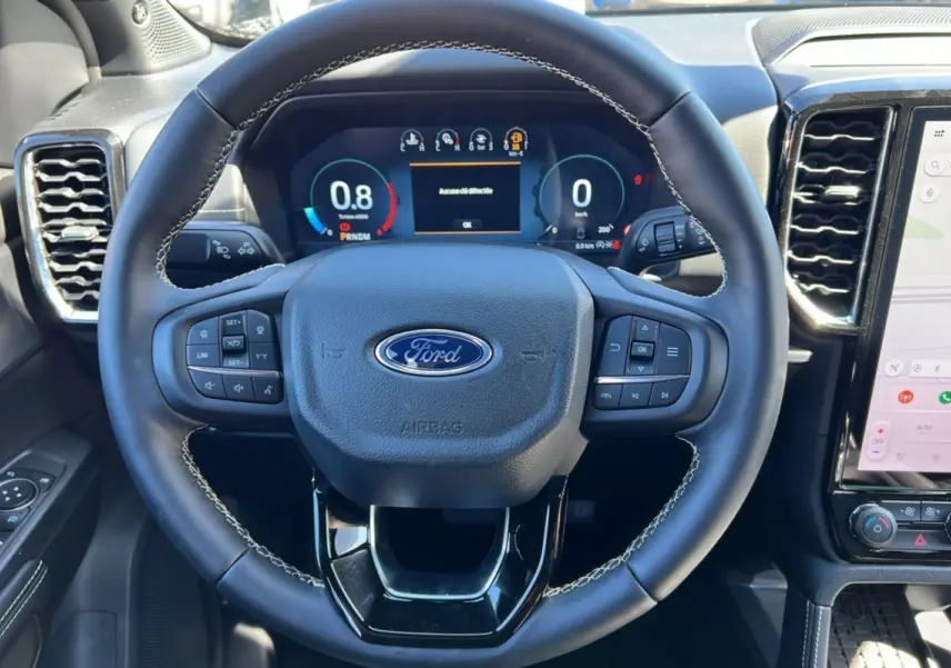 Vue intérieure centrée sur le volant cuir multifonctions du Ford Ranger noir agate avec tableau de bord numérique.