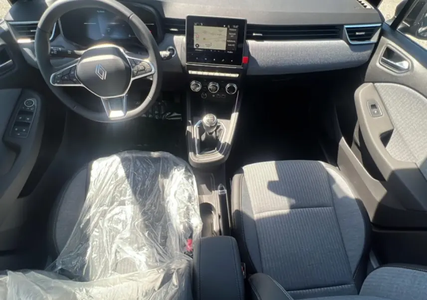 Vue intérieure avant de la Renault Clio V noire, montrant le volant multifonction et la console centrale avec écran tactile.