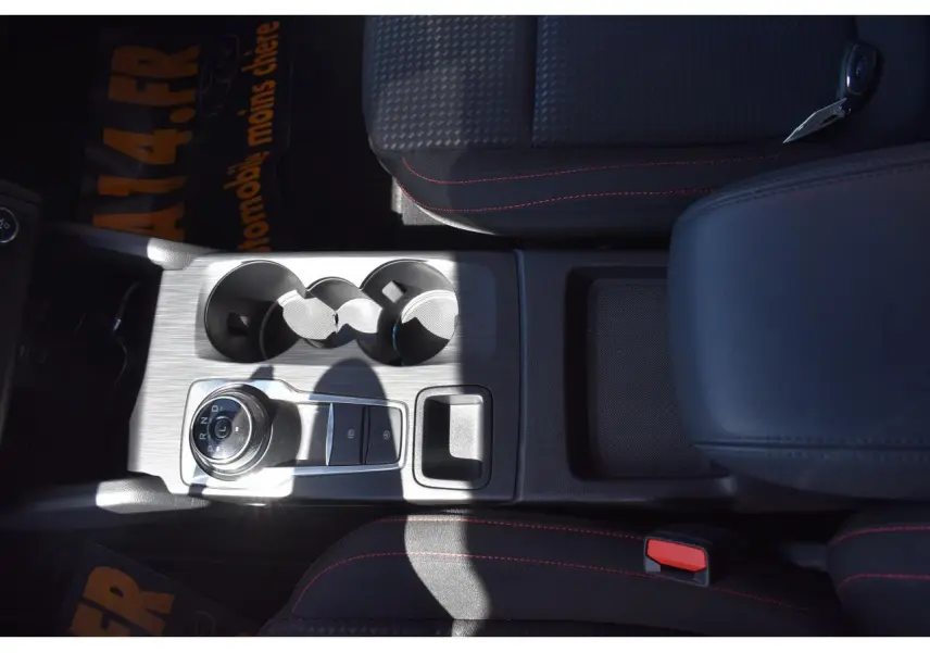 Vue plongeante sur la console centrale de la Ford Focus SW 2025 noire, avec sélecteur rotatif de boîte auto et porte-gobelets.