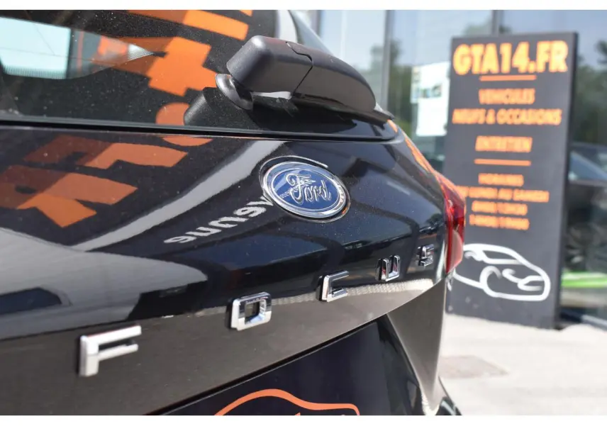 Gros plan sur l'arrière en Agate Black Metallic d'une Ford Focus SW avec logo et lettrage distinctifs visibles.