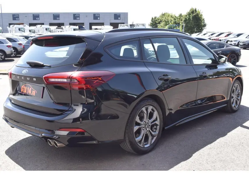 Vue 3/4 arrière droite de la Ford Focus SW 1.5 EcoBlue noire métallisée avec double sortie d'échappement et jantes alliage.