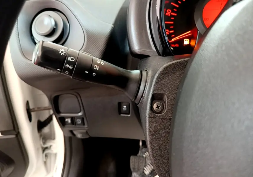 Gros plan sur la manette de phares et clignotants côté gauche du tableau de bord d'une Citroën C1 blanche de 2020.