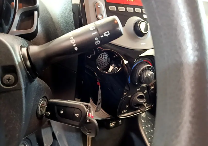 Gros plan sur la console centrale et la clé insérée côté gauche d'une Citroën C1 blanche, avec commandes climatisation visibles.