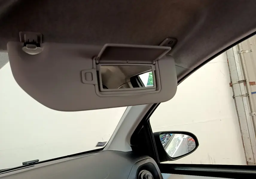 Détail de l'intérieur côté conducteur avec pare-soleil rabattu et miroir de courtoisie ouvert sur Citroën C1 blanc.