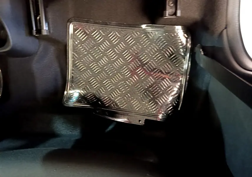 Gros plan sur le tapis de sol en caoutchouc noir à motif damier dans l'habitacle d'une Citroën C1 blanche.