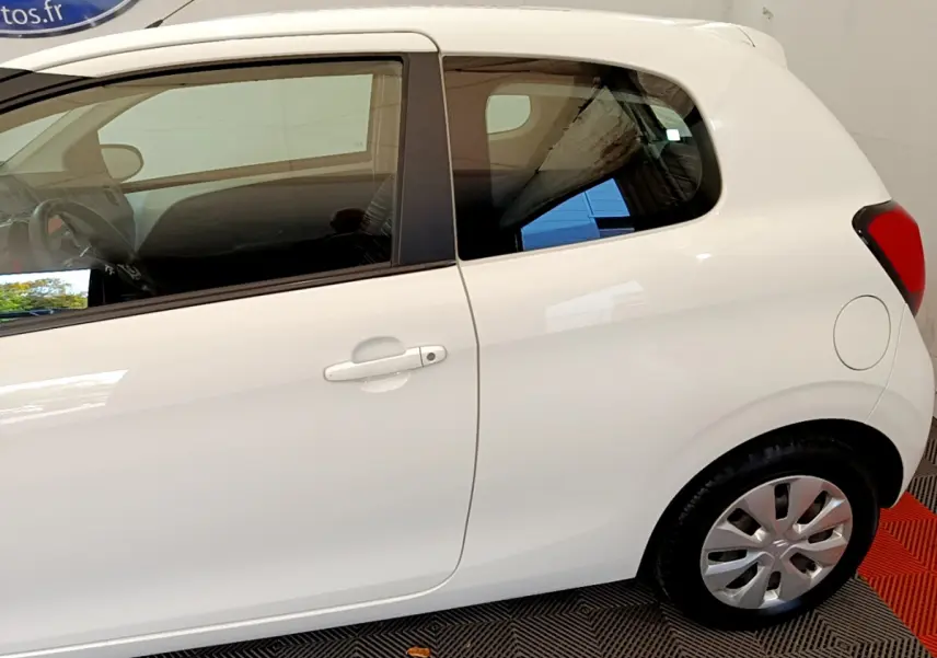 Vue latérale côté droit d'une Citroën C1 blanche 3 portes, mettant en valeur la portière et la roue arrière.