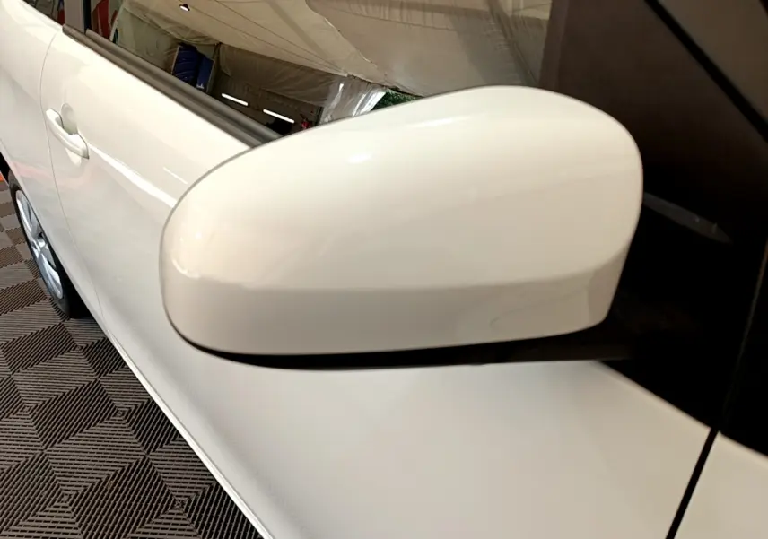 Gros plan sur le rétroviseur côté conducteur blanc d'une Citroën C1 VTi 72 S&S BVM Feel 2020, avec portière visible.