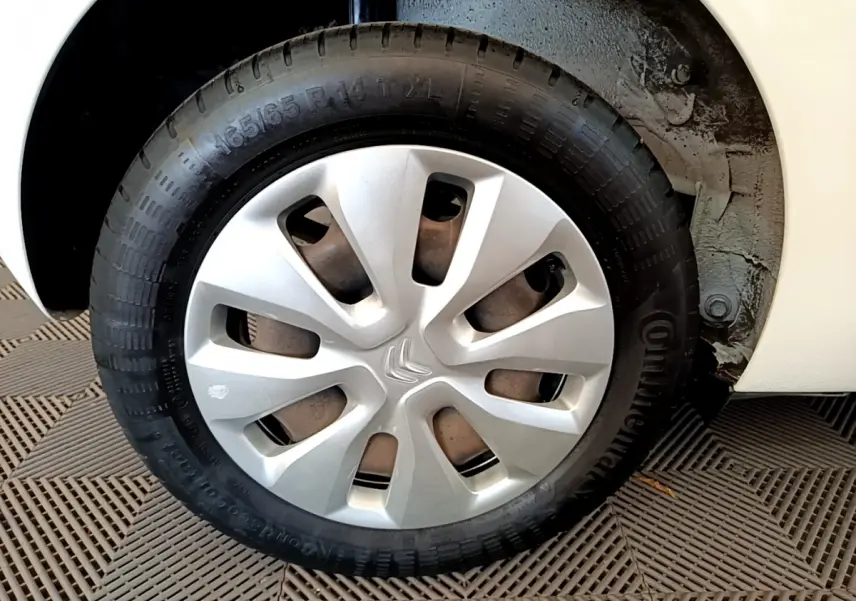 Gros plan sur la roue avant droite d'une Citroën C1 blanche avec enjoliveur argenté et pneu Continental.