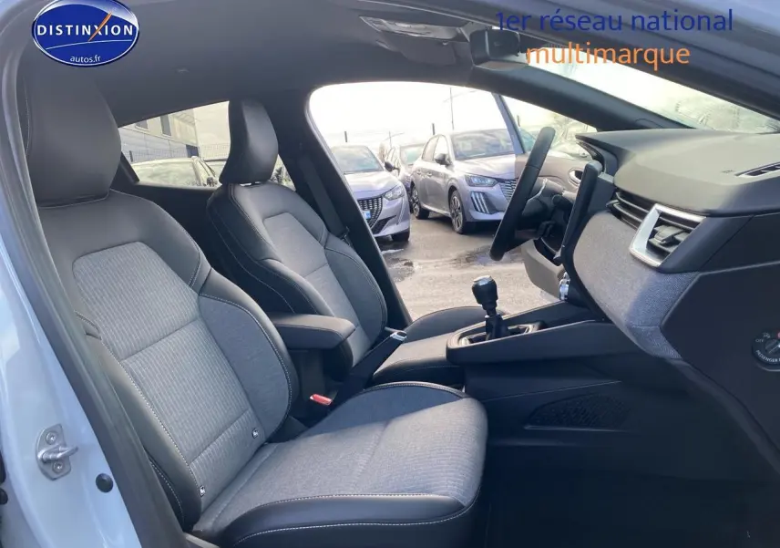 Vue intérieure côté gauche de la Renault Clio V gris rafale, montrant sièges tissu et cuir avec accoudoir central.
