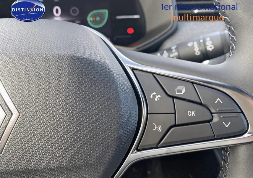 Gros plan sur le volant multifonction de la Renault Clio V, avec commandes audio et téléphone intégrées.