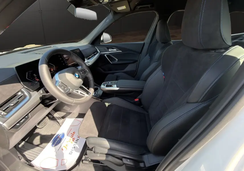Vue intérieure côté conducteur du BMW X1 sDrive20d M SPORT 2025 avec sièges noirs et tableau de bord moderne.
