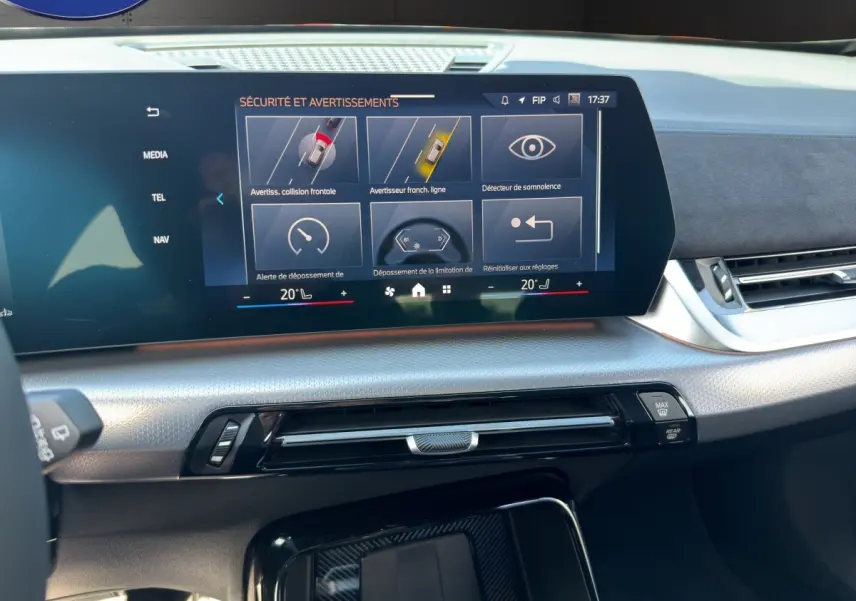 Vue rapprochée de l'écran tactile central du tableau de bord du BMW X1 blanc, affichant les alertes de sécurité.