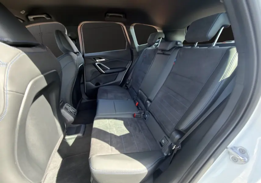 Vue intérieure côté droit des sièges arrière en cuir et alcantara noirs du BMW X1 sDrive20d blanc 2025.