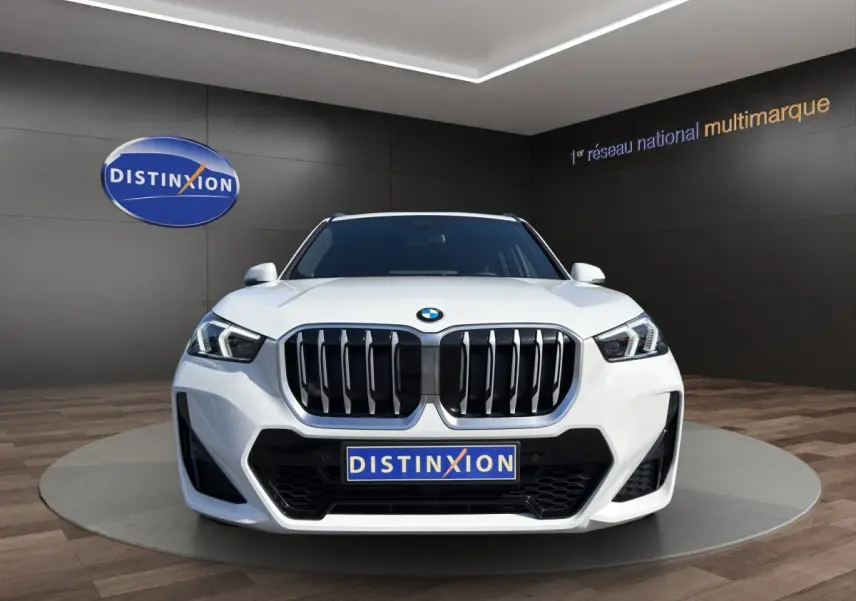 BMW X1 sDrive20d blanc vue de face avec calandre imposante et phares LED dans un showroom