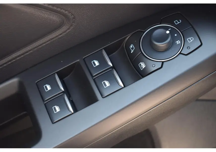 Gros plan sur les commandes de lève-vitres et rétroviseurs sur la portière côté conducteur de la Ford Focus SW 2025.