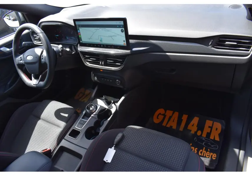 Vue intérieure côté conducteur de la Ford Focus SW 2025, montrant tableau de bord noir et écran tactile central.