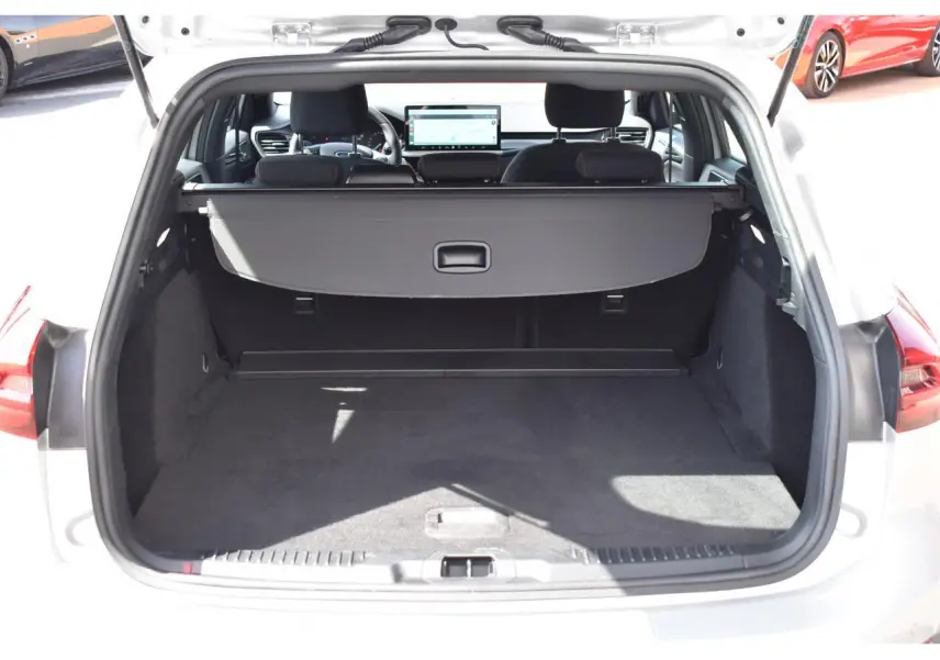 Vue arrière du coffre ouvert d'une Ford Focus SW 1.5 EcoBlue 115 Powershift ST LINE X Moondust Silver, montrant l'espace de chargement et la tablette cache-bagages.
