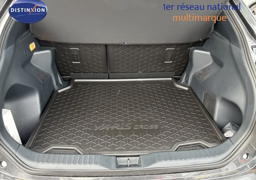Coffre ouvert de la Toyota Yaris Cross gris atlas metal, vue de l'arrière montrant le tapis de coffre avec logo Yaris Cross.