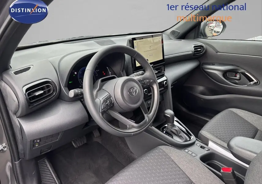 Vue intérieure côté conducteur de la Toyota Yaris Cross gris atlas, avec volant multifonction et écran tactile central.
