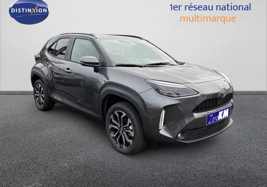 Toyota Yaris Cross gris atlas métal vue 3/4 avant droit avec jantes noires et feux LED allumés.