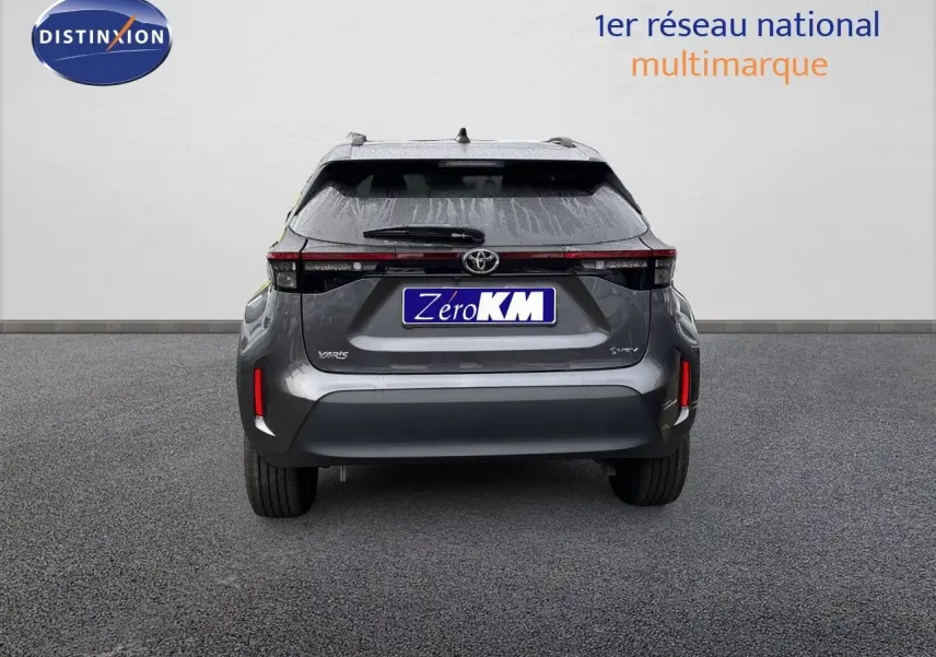 Vue arrière d'une Toyota Yaris Cross gris atlas métal avec feux arrière LED et logo hybride visible.