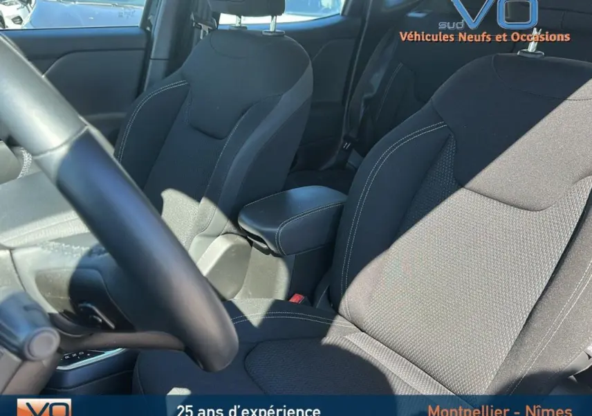 Intérieur du Jeep Renegade 2024 noir, vue sur sièges avant avec accoudoir central et volant partiellement visible.