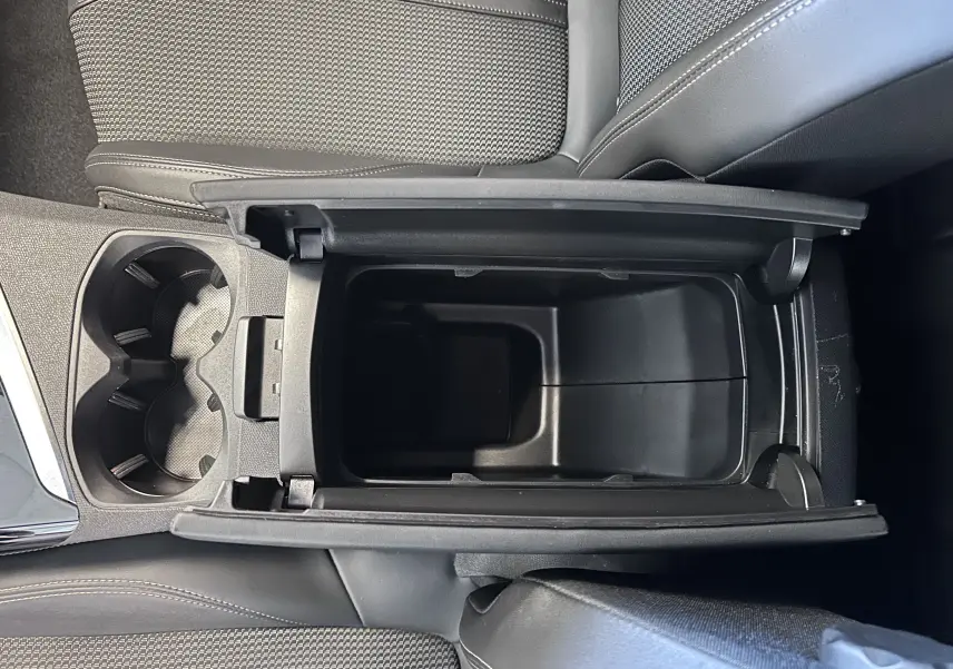 Vue plongeante sur l'accoudoir central ouvert et les porte-gobelets du Peugeot 3008 blanc nacré, intérieur noir.