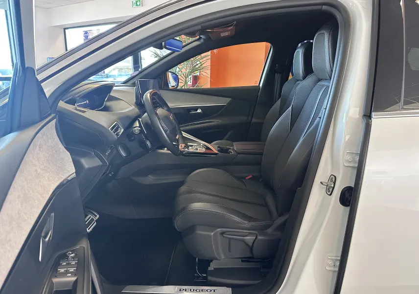 Intérieur côté conducteur du Peugeot 3008 blanc nacré 2022, sièges cuir noirs et tableau de bord moderne.