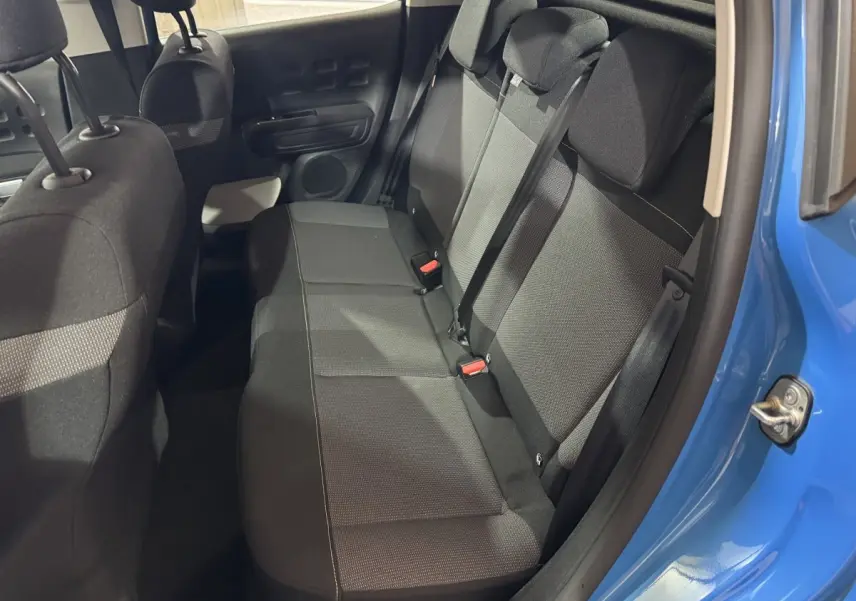 Vue intérieure côté droit sur la banquette arrière noire d'une Citroën C3 bleu 2018 avec ceinture de sécurité attachée.