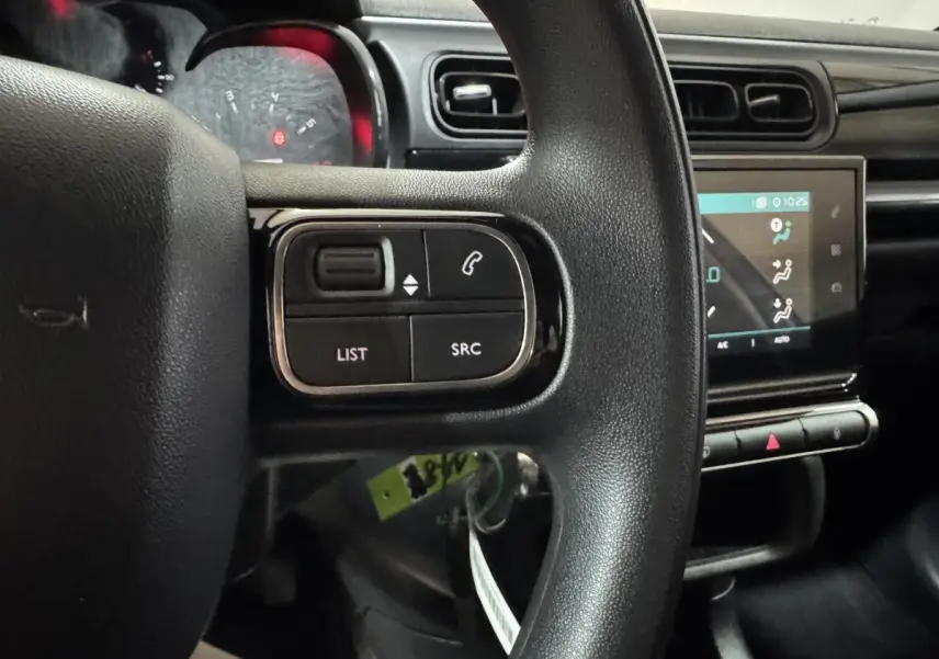 Vue intérieure centrée sur le volant noir avec commandes, écran tactile et tableau de bord de la Citroën C3 bleu.