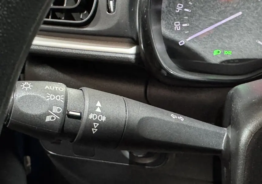 Gros plan sur la manette de commande des phares et clignotants dans l’habitacle d’une Citroën C3 2018 noire.