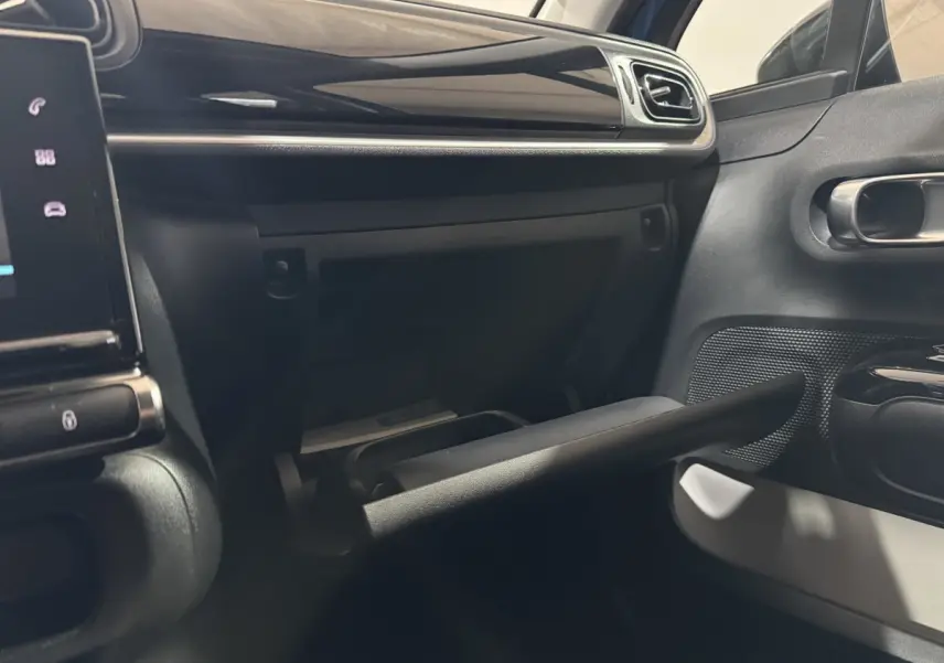 Intérieur de la Citroën C3 bleu, vue sur la boîte à gants ouverte côté passager avec tableau de bord noir.